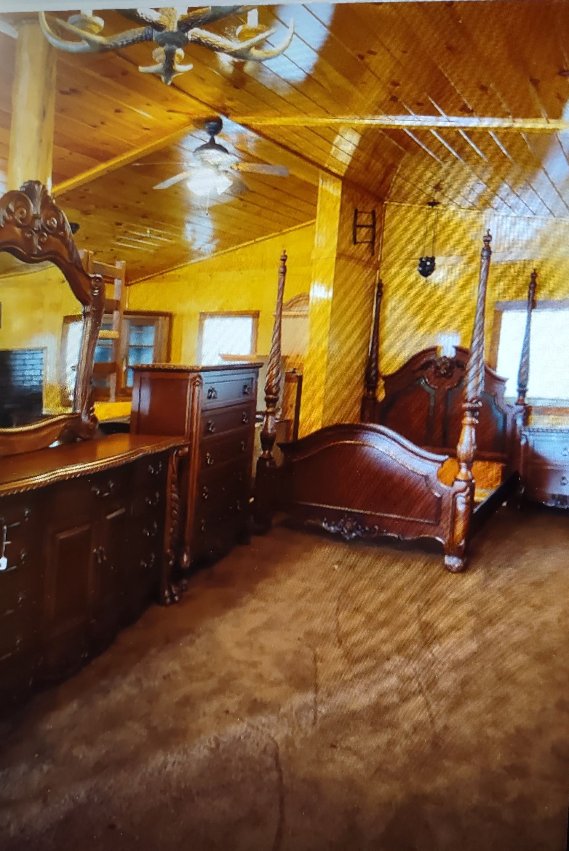A bedroom with a bed , dresser , mirror and ceiling fan.