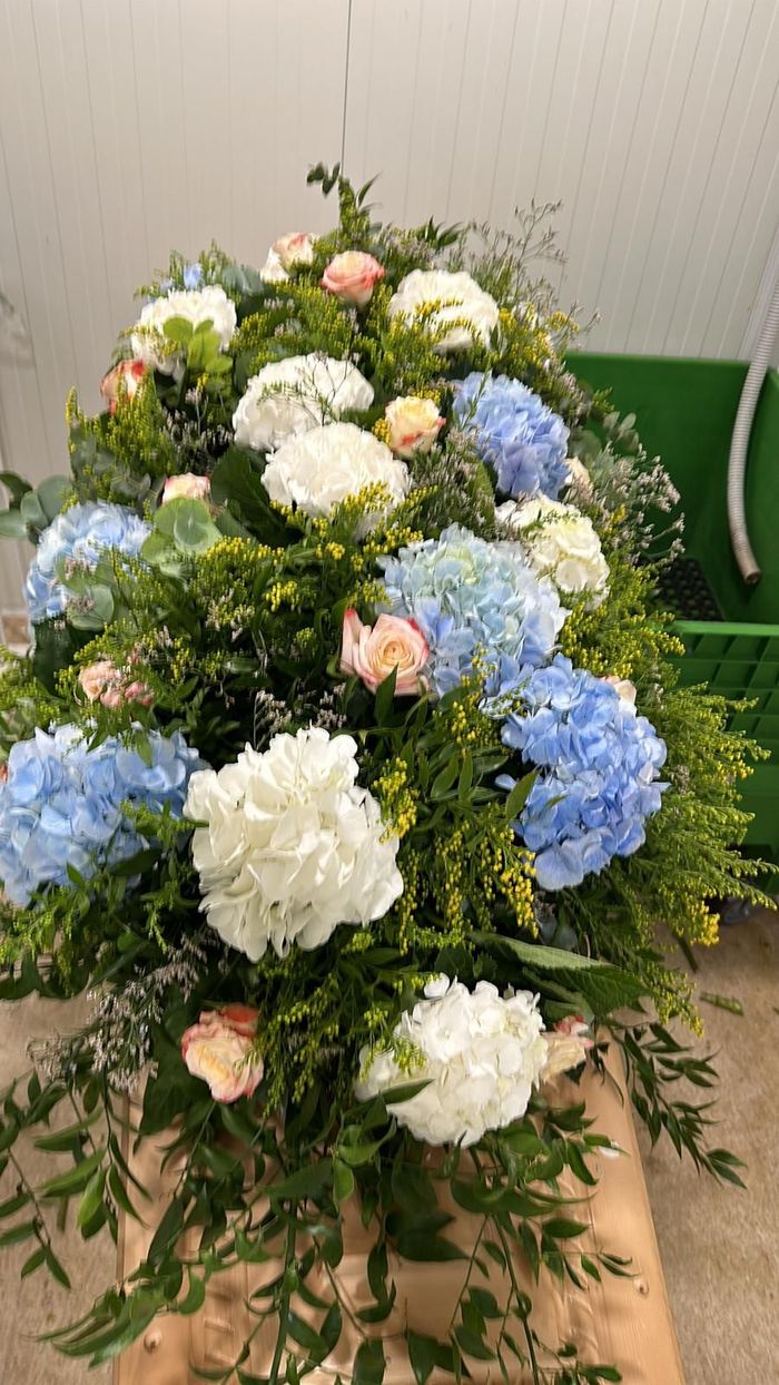 Composizione floreale con ortensie blu, bianche e color pesca e verde.