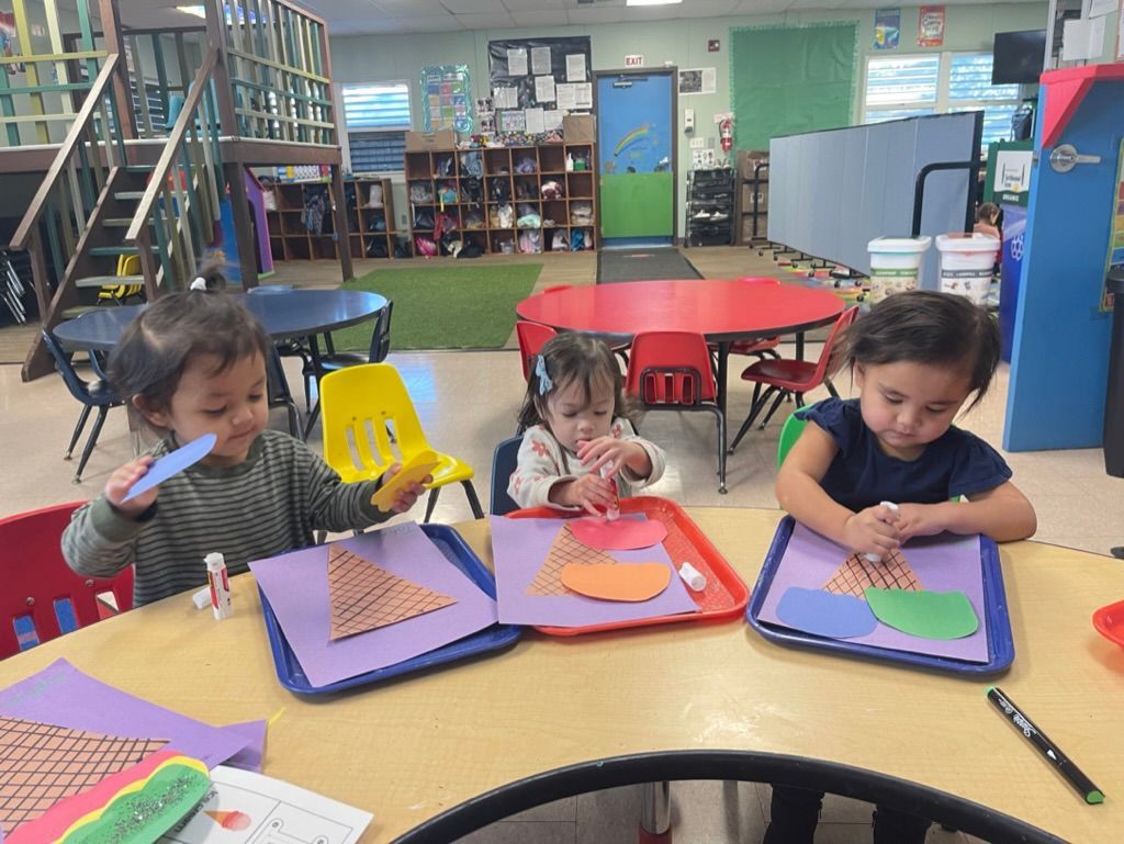 Children in classroom listen to teacher, holding percussion instruments.