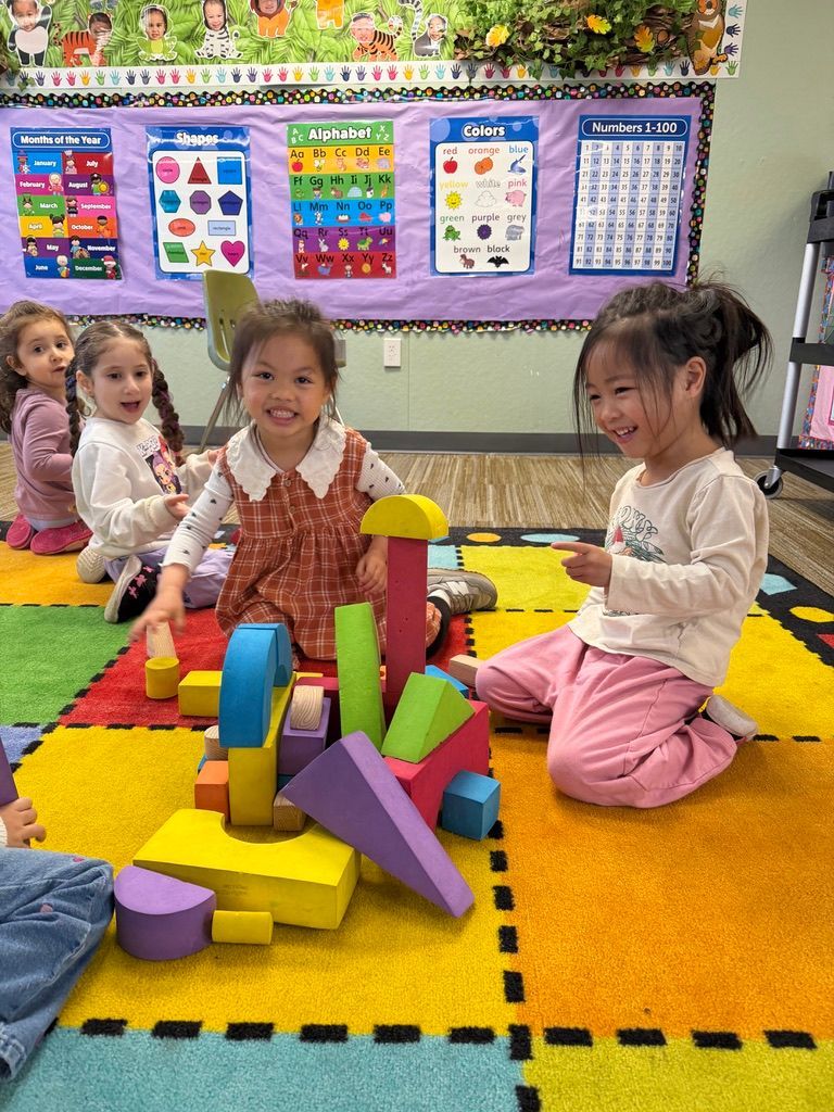 Children and adult seated on floor playing with colorful cards.