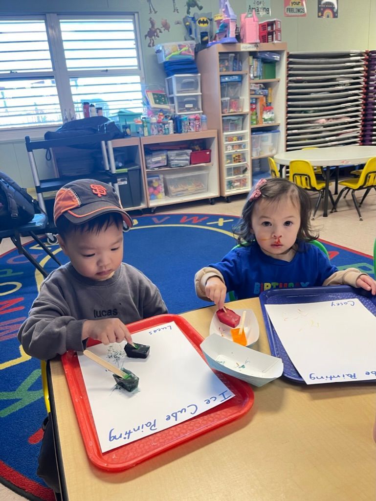 Group of smiling children lying on colorful mats in a circle, looking up.