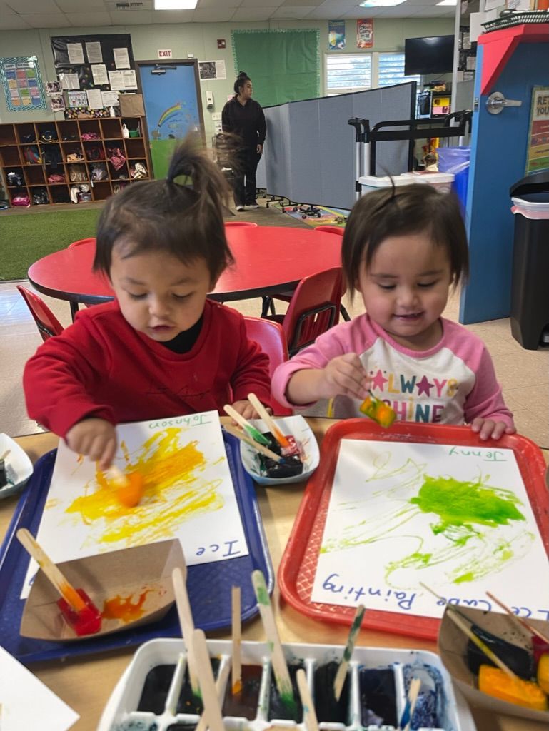 Children playing with puzzles and stacking rings on a table.