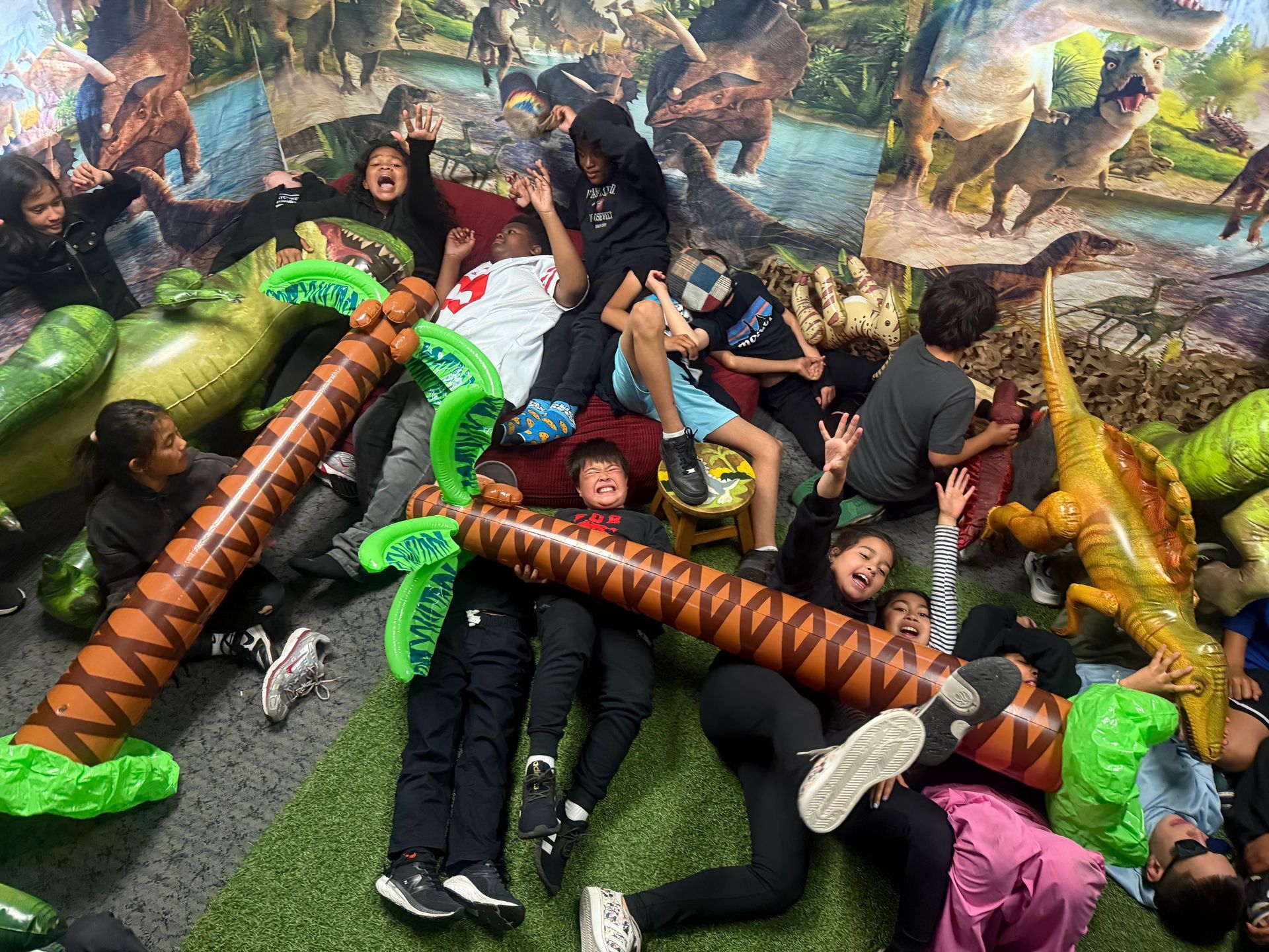 Preschool graduation ceremony with children in caps and gowns on stage. Parents watch from the audience.