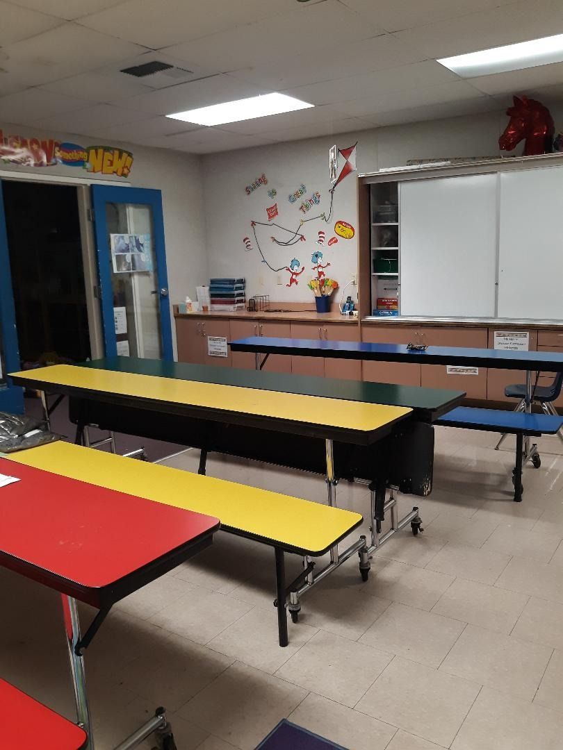 Empty school cafeteria with colorful tables.