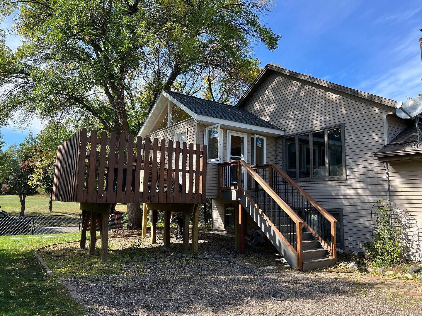 Wooden deck with railing attached to a house with a small covered porch.