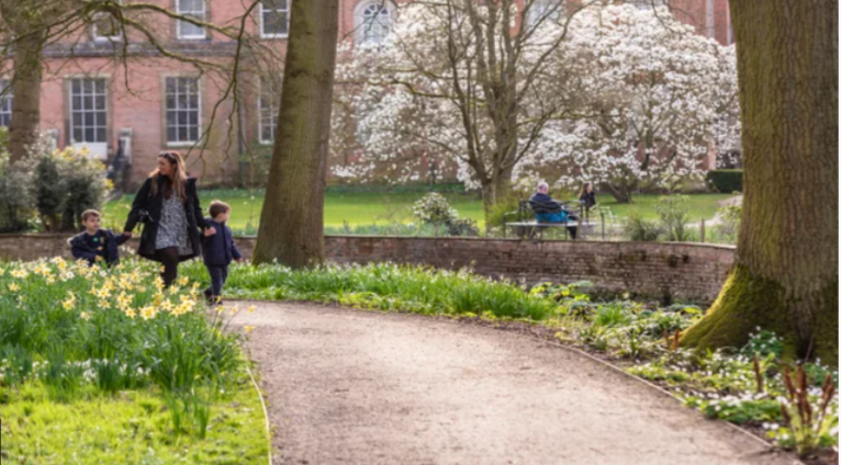 A woman and two children are walking down a path in a park. National trust work