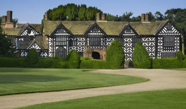 A large black and white house with a path leading to it National trust work