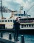 A man is fishing in front of a boat in the water.