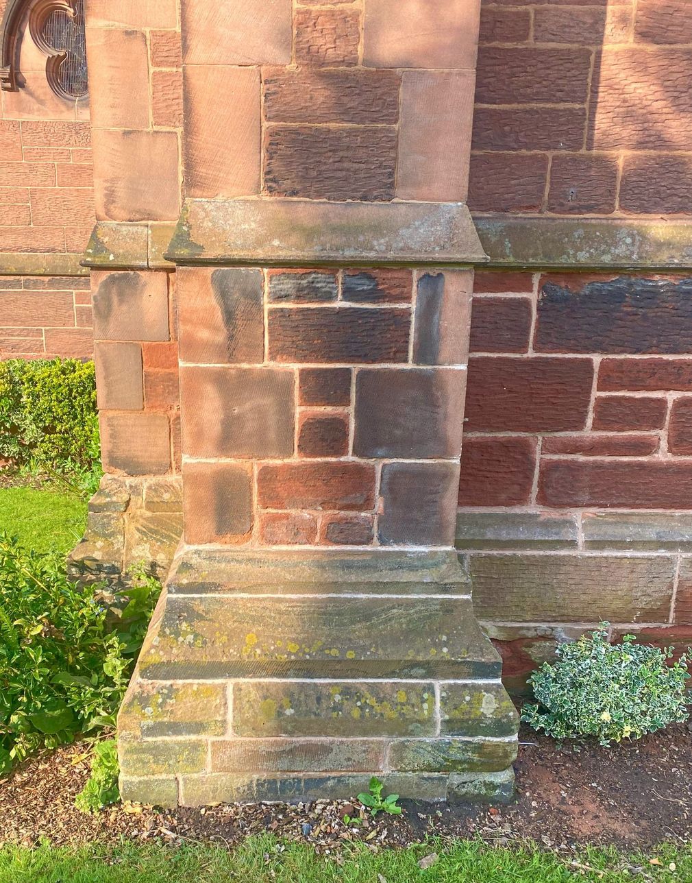 A close up of a stone church wall with a stone base