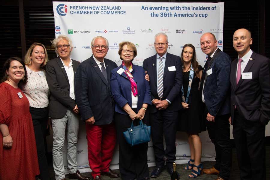 Group of people posing at an event for the 36th America's Cup, with the French New Zealand Chamber of Commerce logo visible.