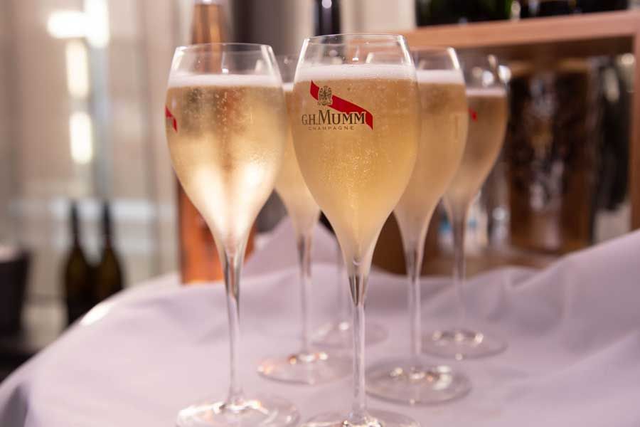 Glasses of champagne on a tray. Bubbles in the clear liquid. Bright lighting.