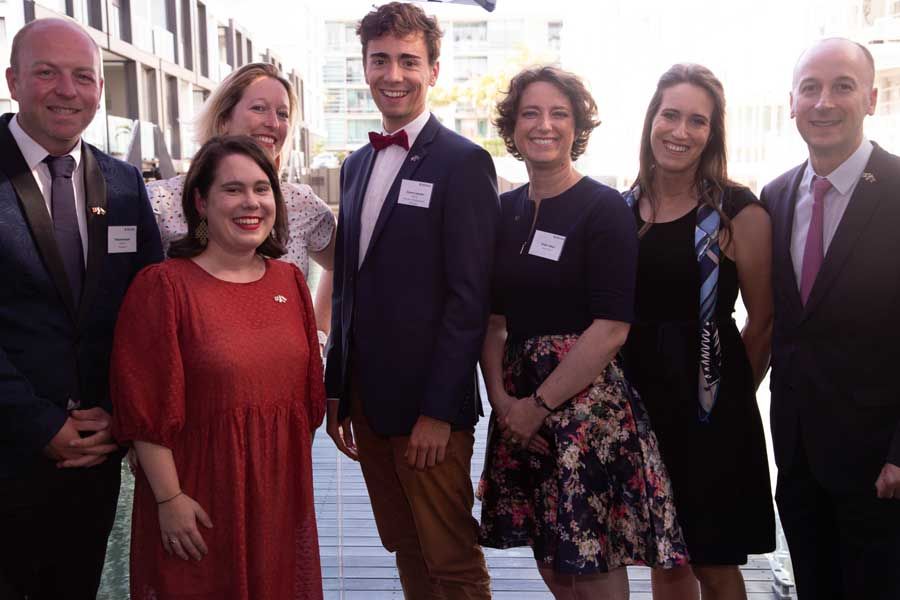 Group of people, mostly in business attire, smiling and posing outdoors.