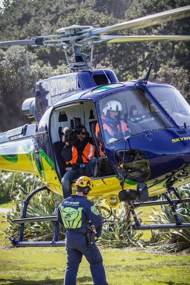 Helicopter with medics; one in the cockpit, one on the ground; blue, yellow, and green colors.