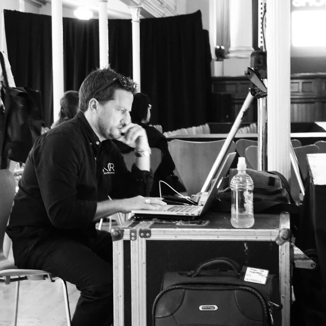 Craig Walsh seated at a laptop, leaning forward with a hand to his chin. Pink Floyd Experience .