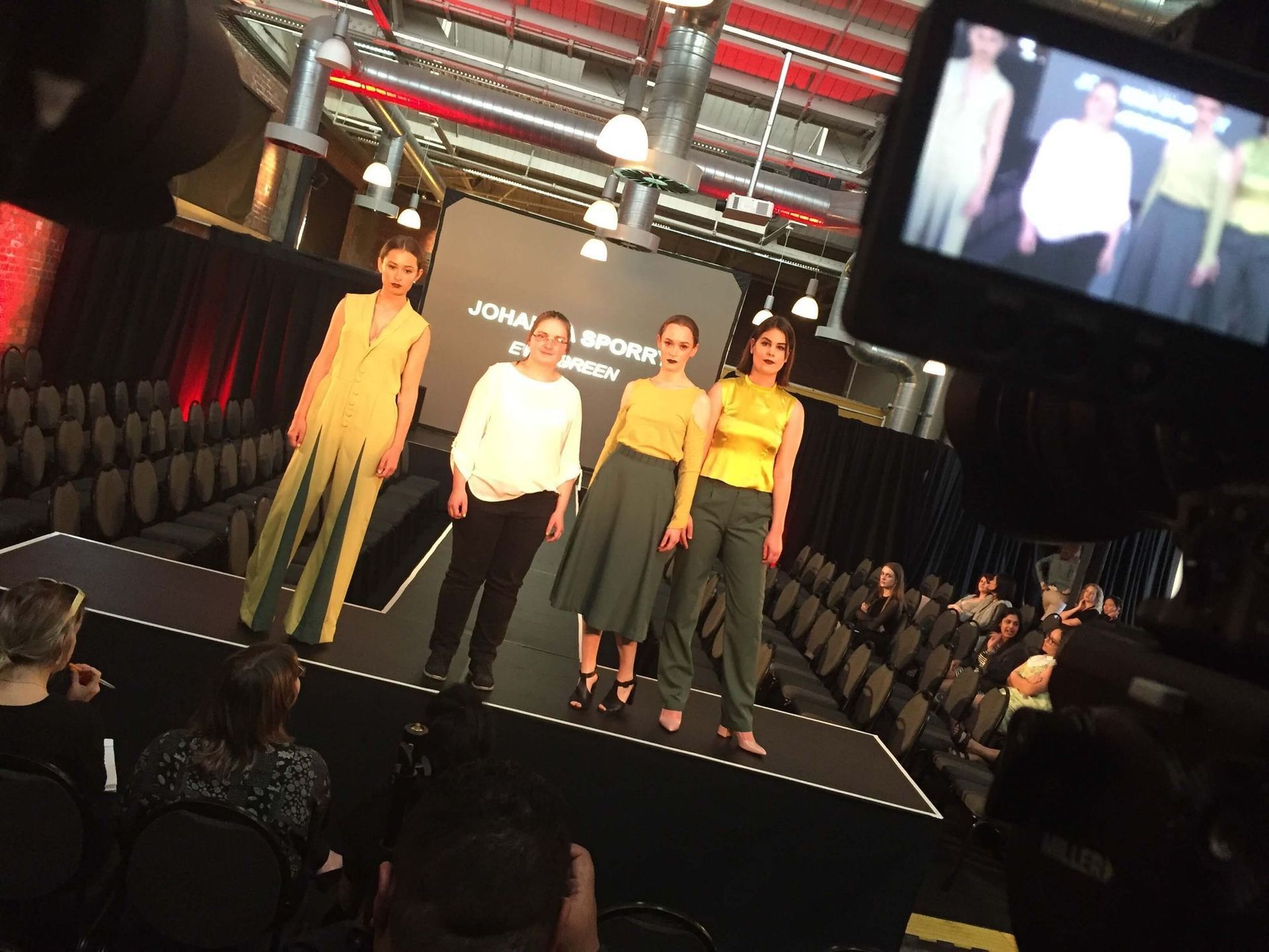 Models on runway at fashion show, wearing yellow and green outfits.