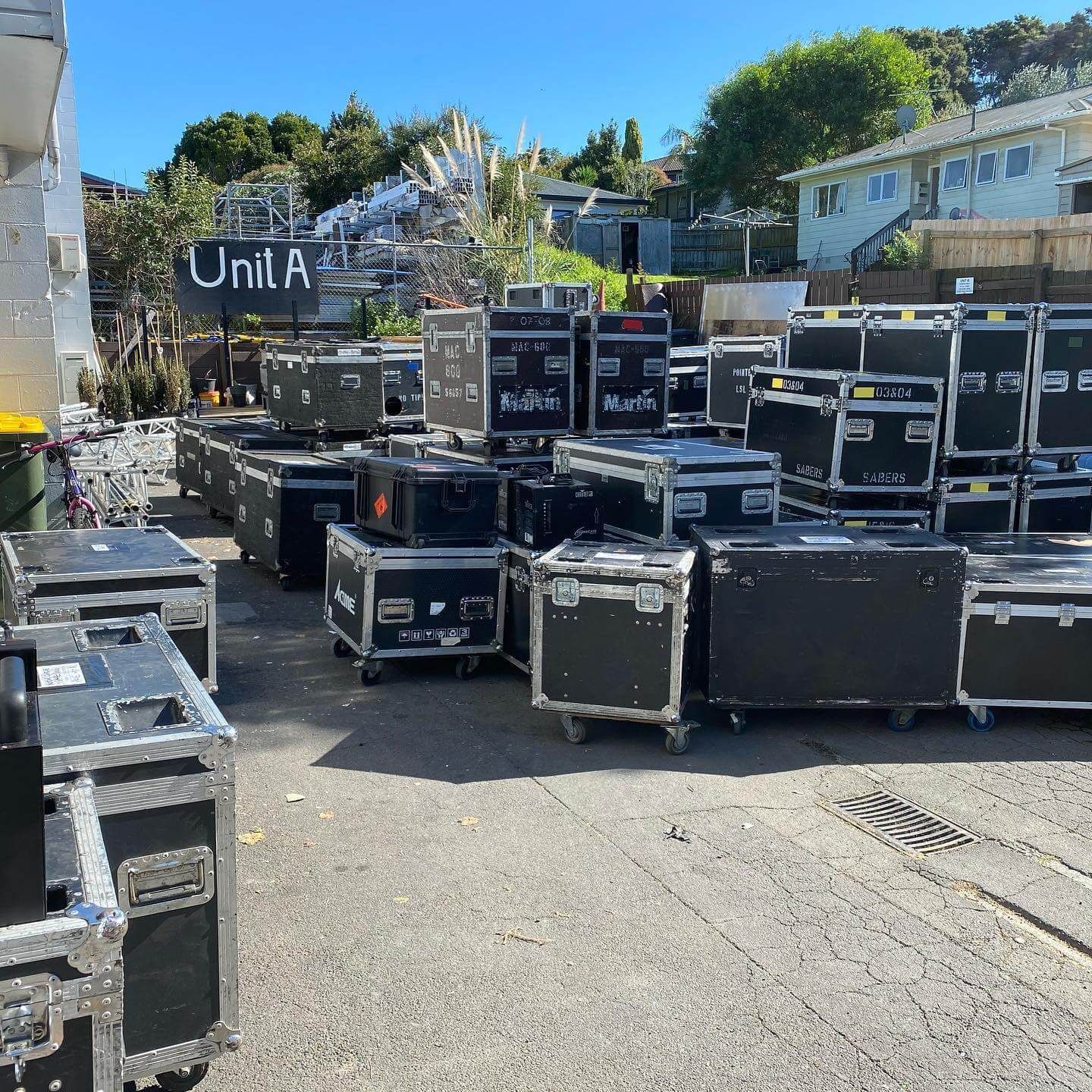 Outdoor shot of numerous black music equipment cases stacked on a paved area for the Pink Floyd Experience 