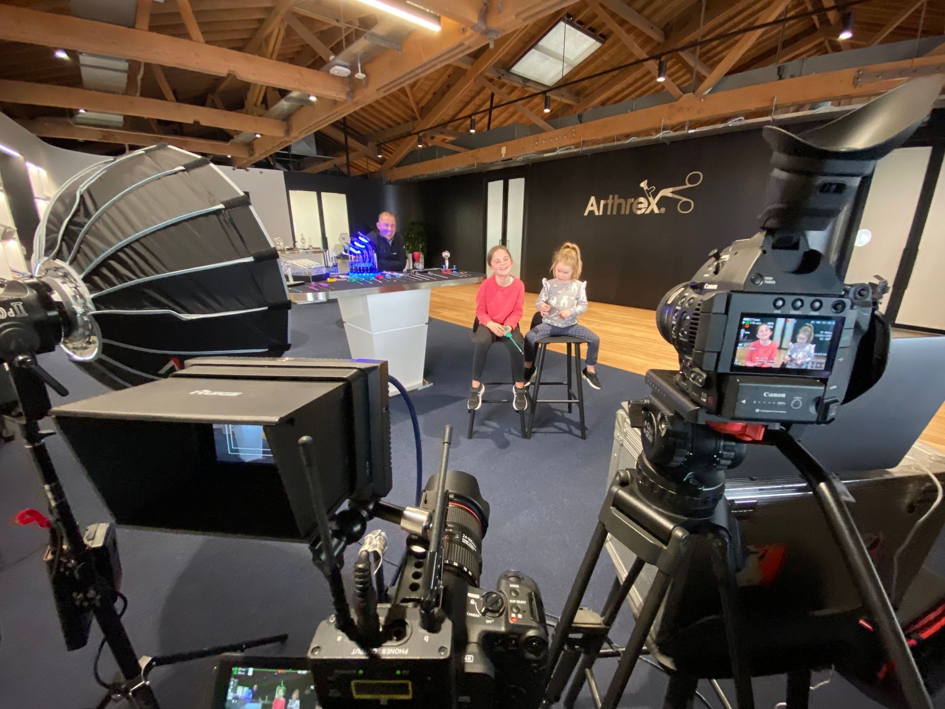 Video studio setup with two children being filmed. Cameras, lights, and equipment are visible.