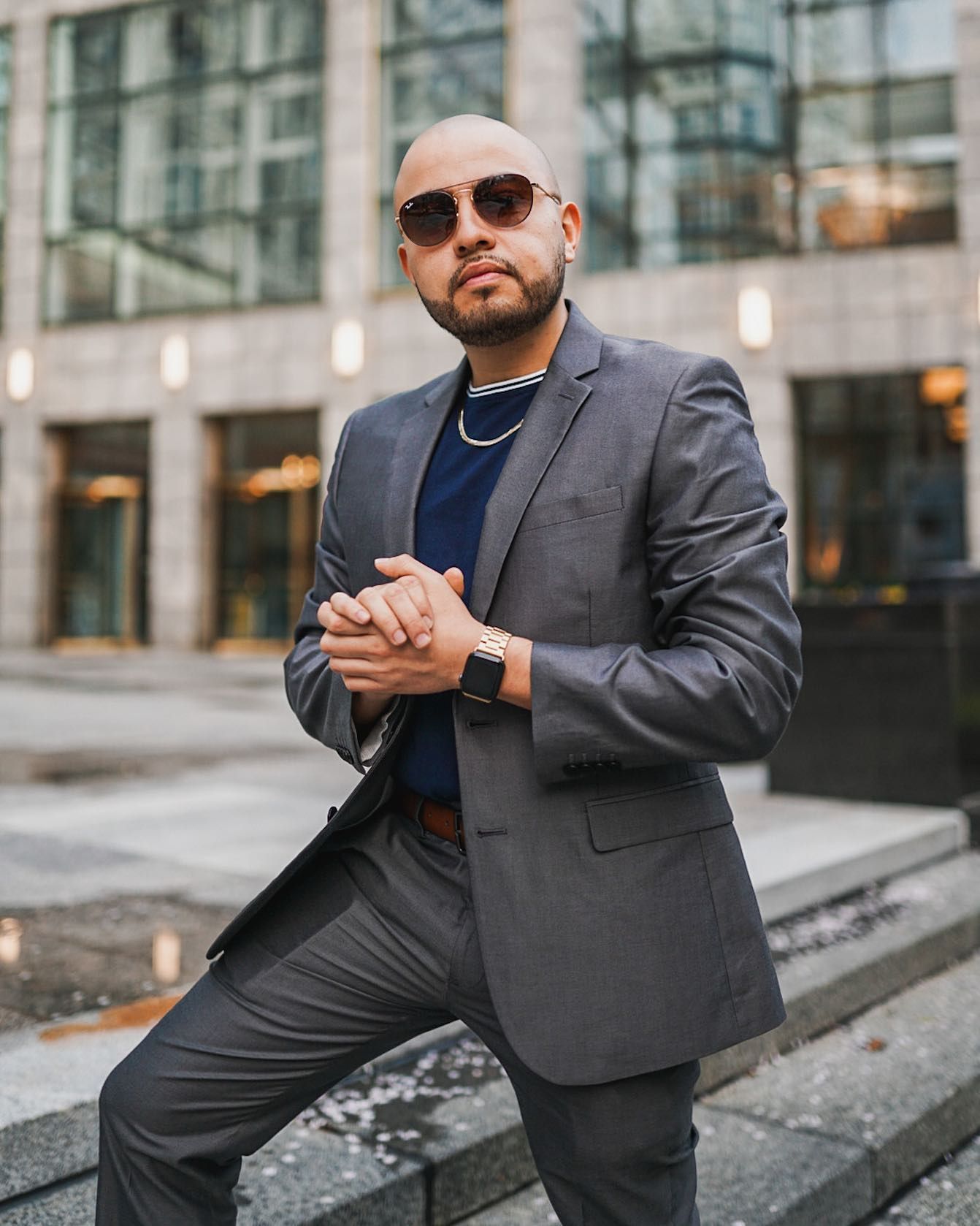 A man in a suit and sunglasses is standing on steps in front of a building.
