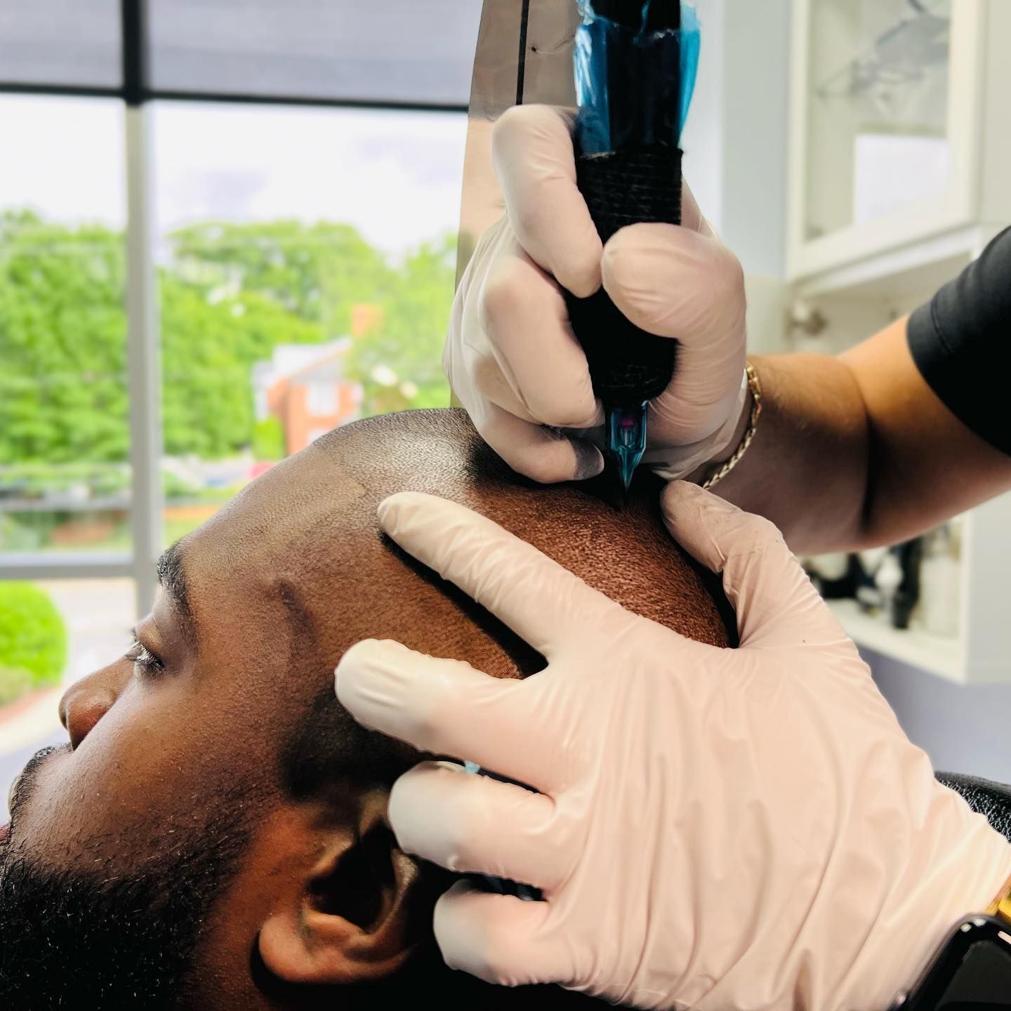 A man with a beard is getting a tattoo on his head