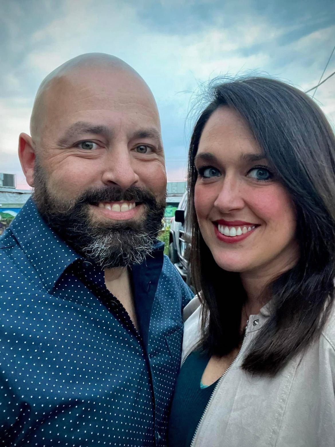 A man and a woman are posing for a picture together and smiling.