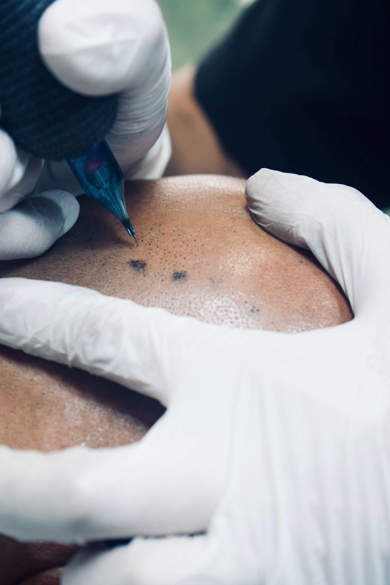 A man is getting a tattoo on another man 's head.