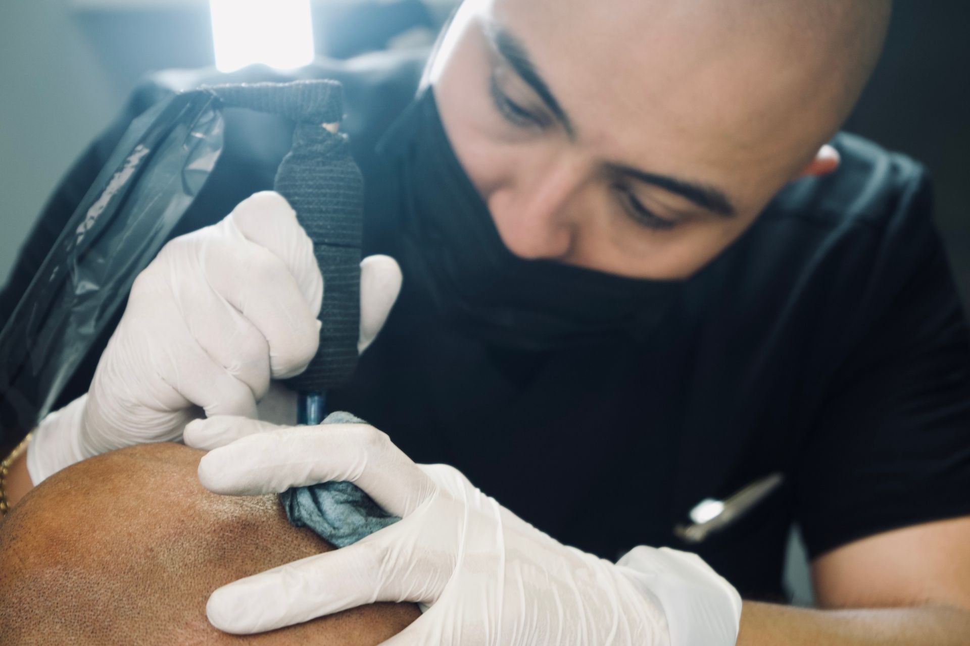 A man is getting a tattoo on another man 's head.