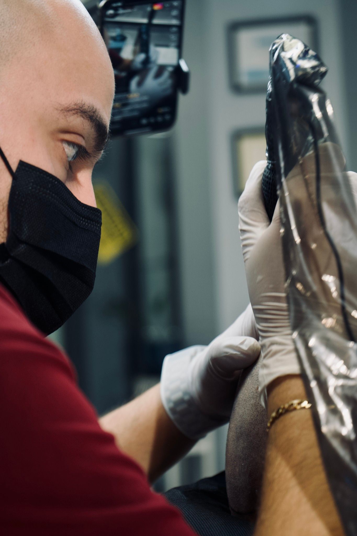 A man wearing a mask and gloves is getting a tattoo