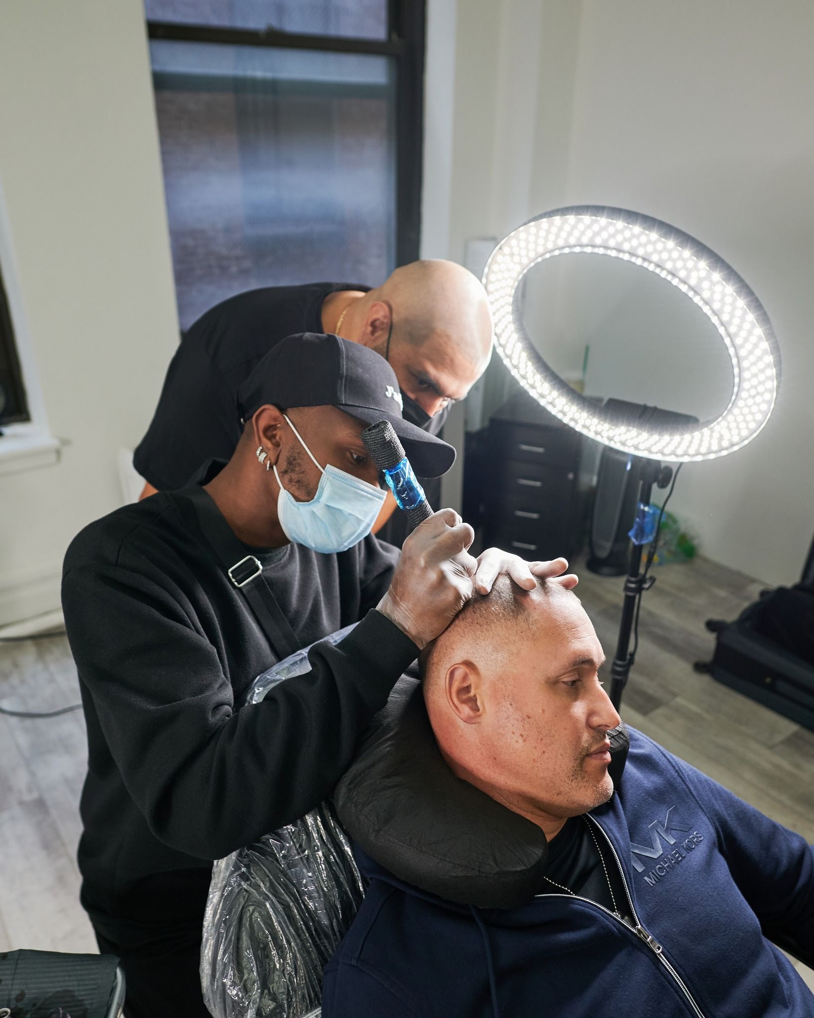 A man is getting his hair cut by a barber while wearing a mask.