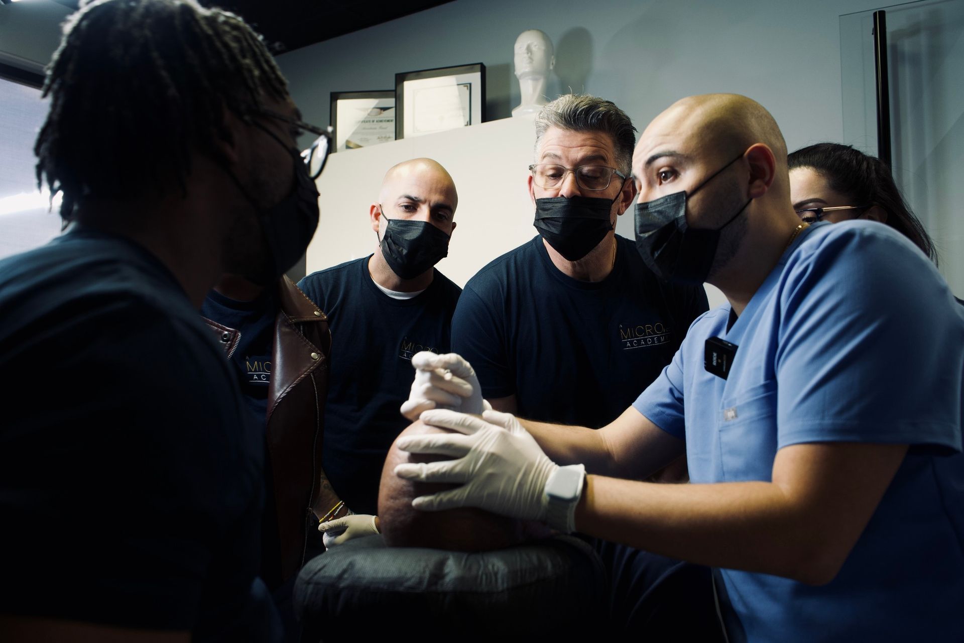 A group of men wearing masks are looking at a man 's head.