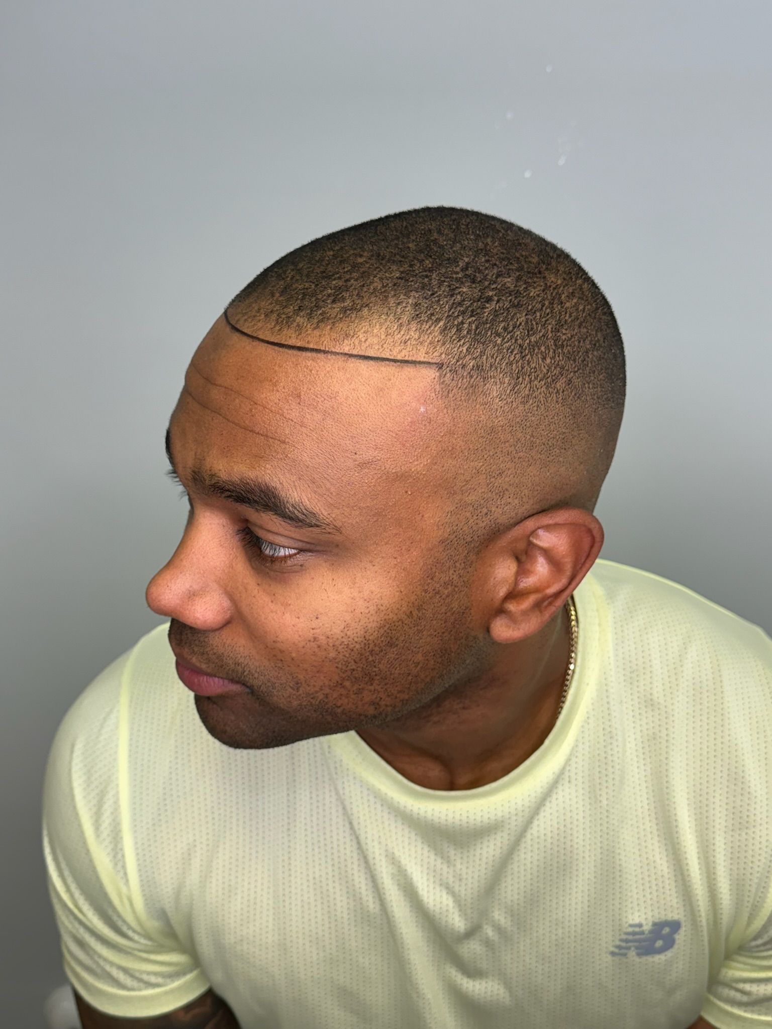 A man with a shaved head is wearing a new balance shirt.