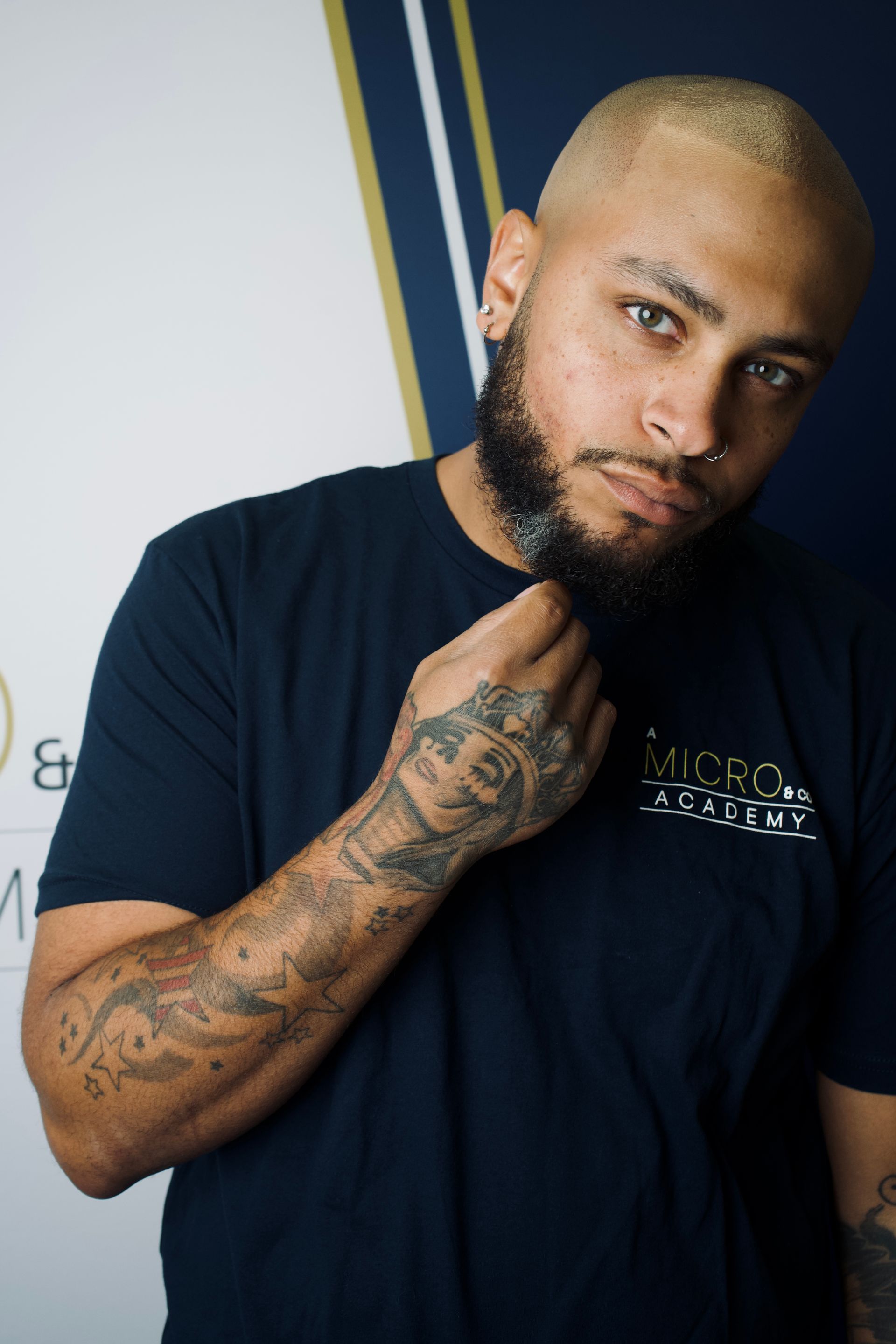 A man with a tattoo on his arm is holding a beard brush.