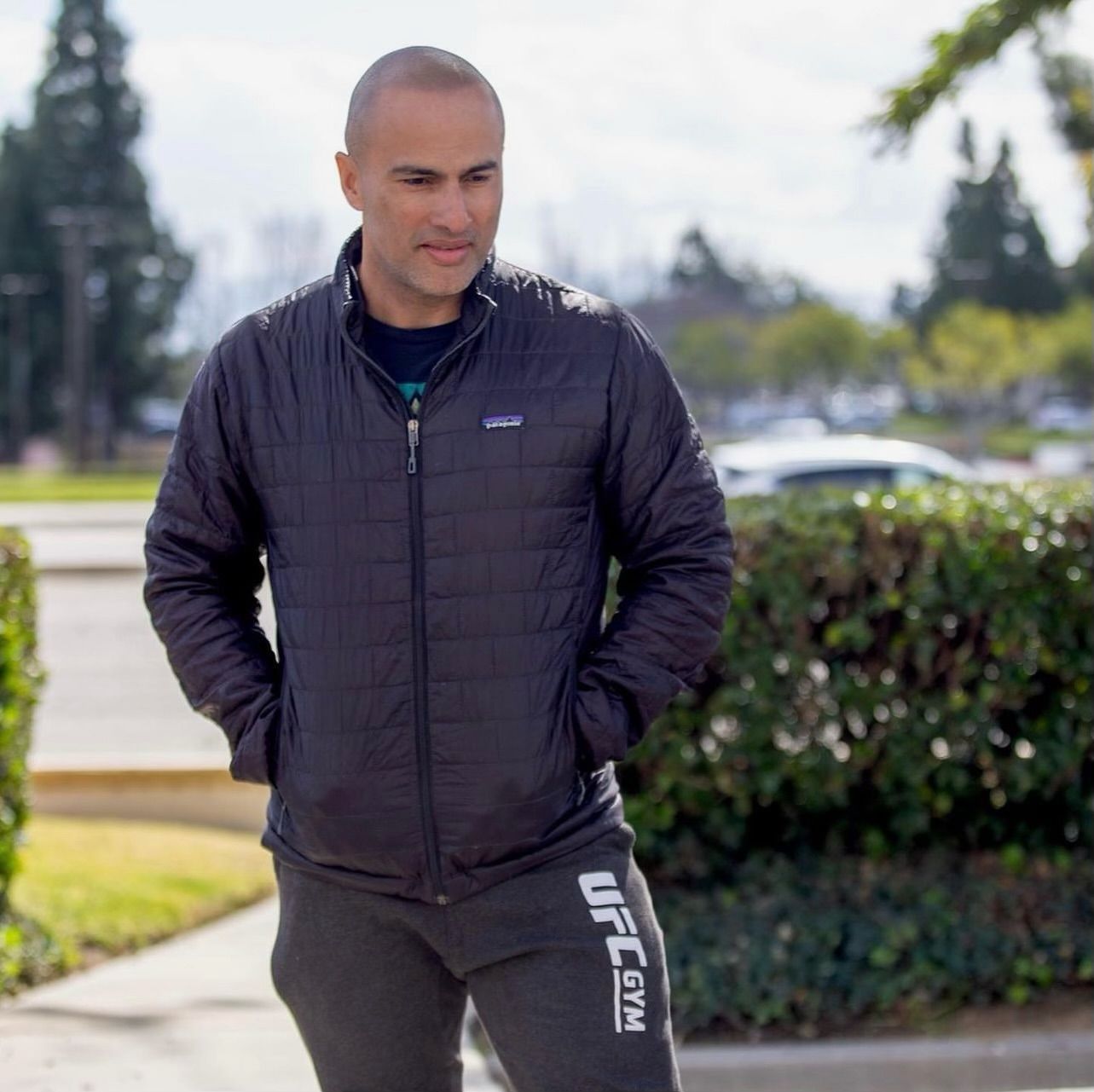 A man wearing a black jacket and ufc gym pants