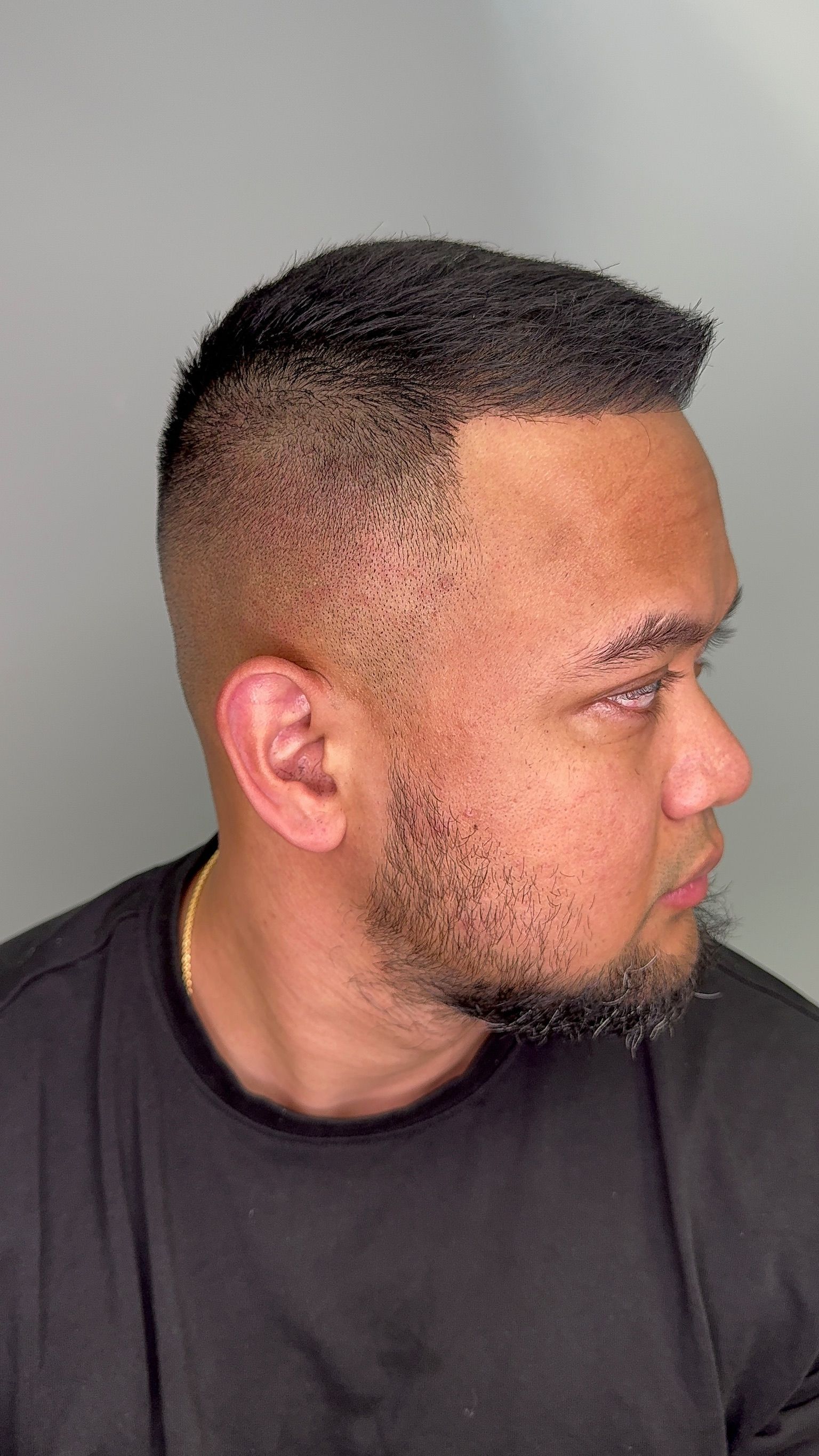 A man with a beard is wearing a black shirt and looking at the camera.