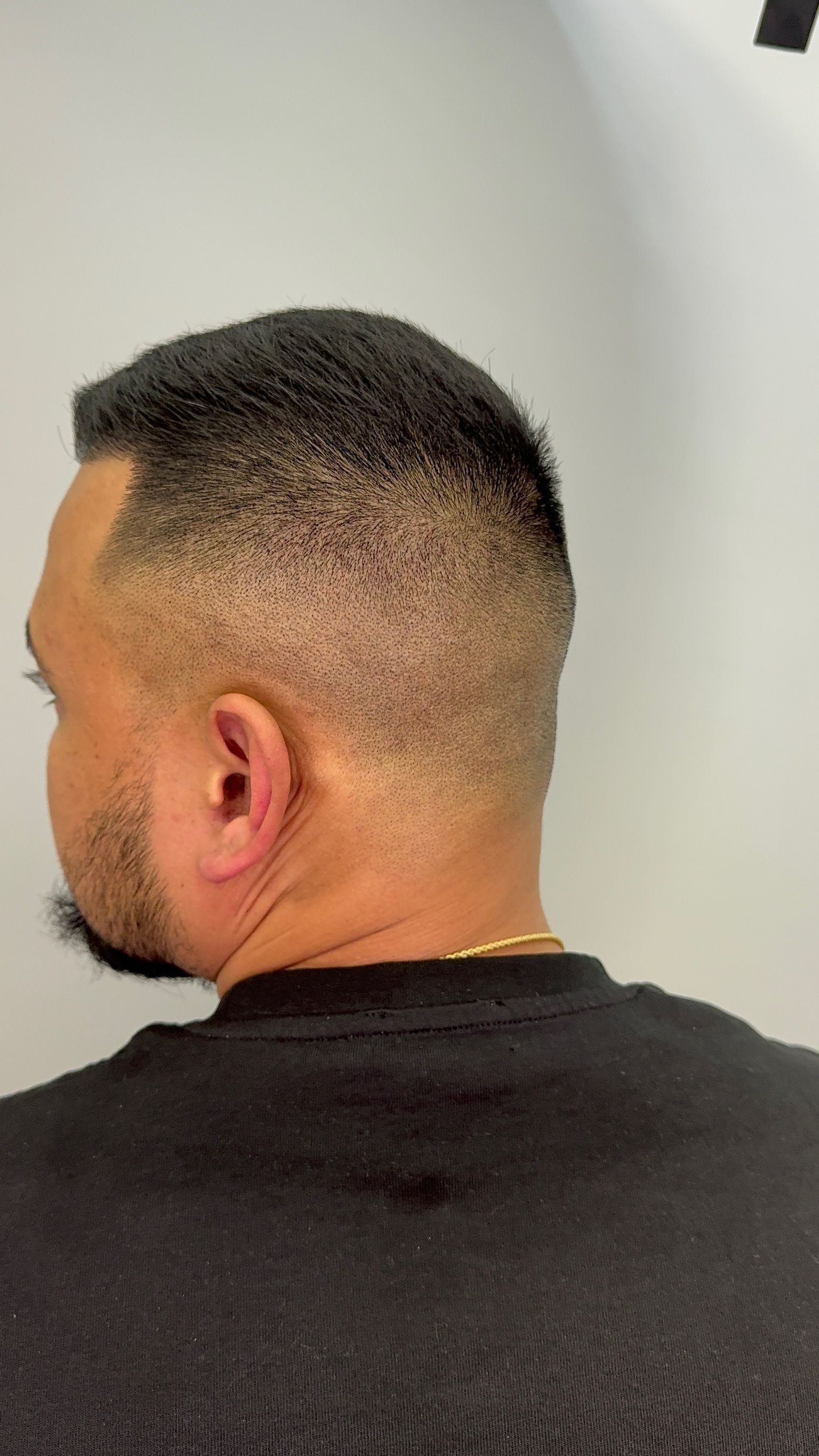 The back of a man 's head with a shaved head and a beard.
