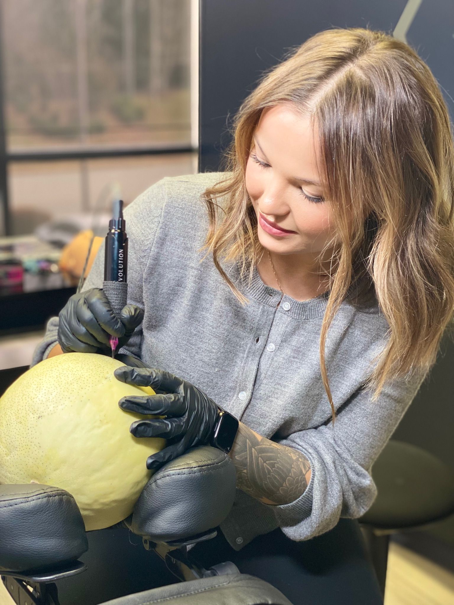 A woman wearing black gloves is carving a pumpkin.