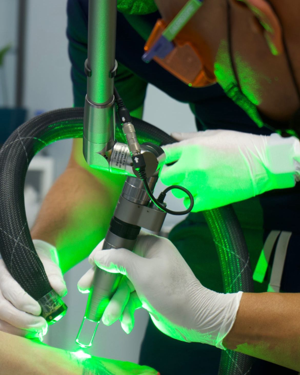 A person wearing white gloves is using a machine that has a green light on it