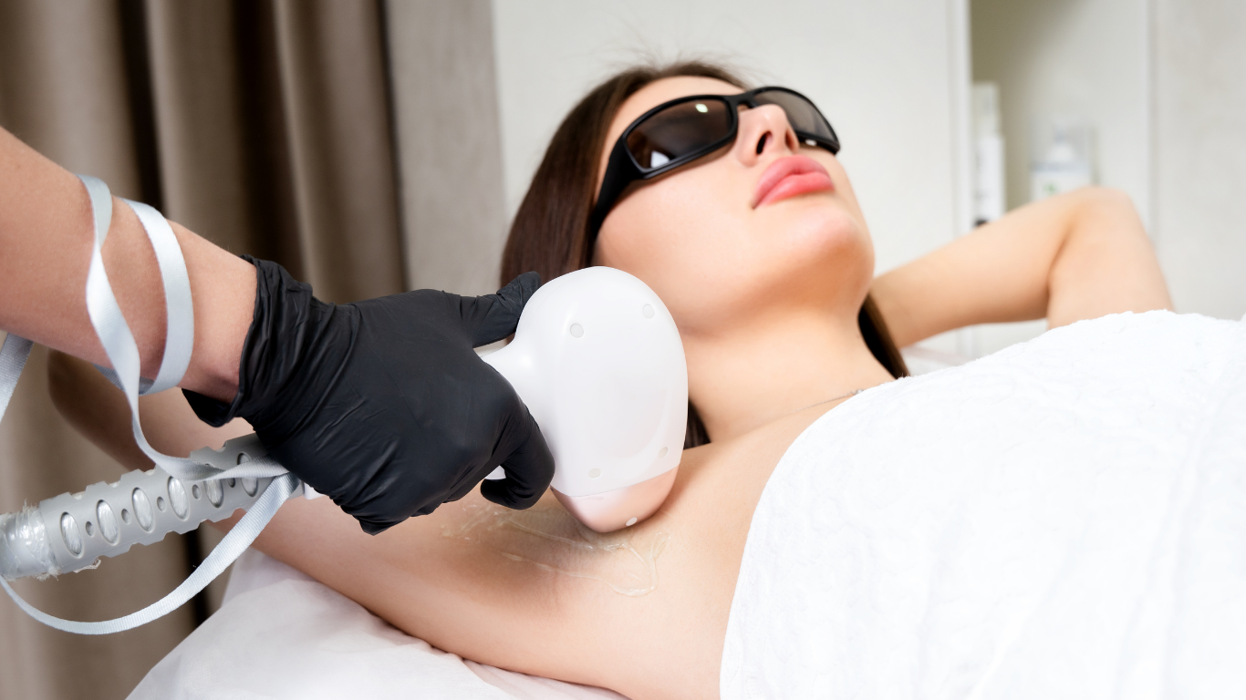 Woman receiving underarm laser hair removal. Technician holding device, wearing black gloves.