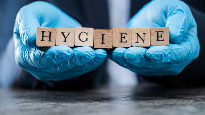 Hands in blue gloves holding wooden blocks spelling