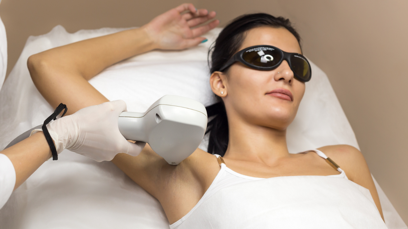 Woman receiving laser hair removal treatment on her underarm; wearing eye protection.