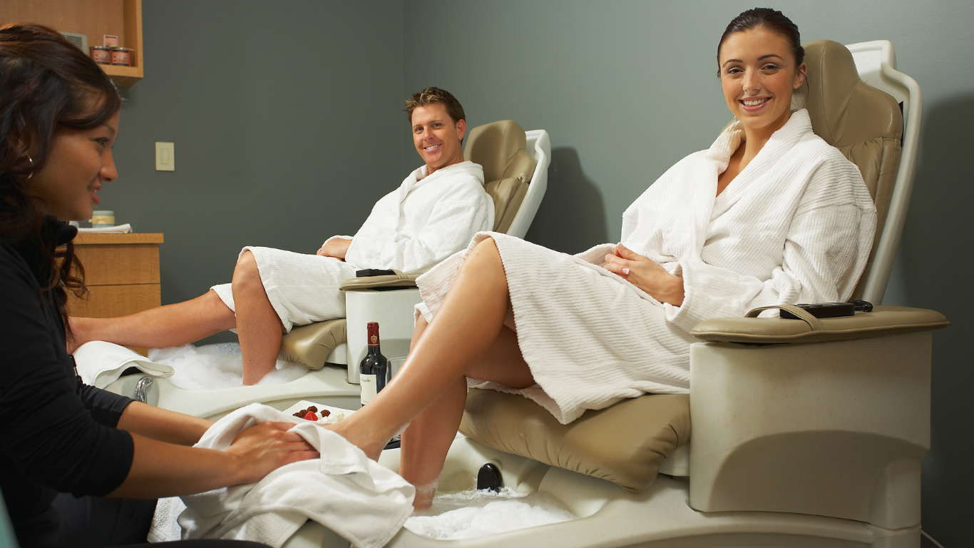 Woman giving foot massage to two people in spa.