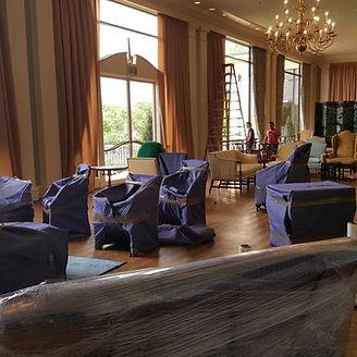 Room with furniture covered in blue protective wrap, ready for moving.