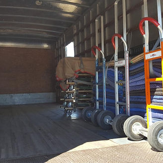 Inside of a truck with stacked pads, hand trucks, and covered furniture ready for a move.