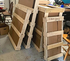 Cardboard boxes inside wooden shipping crates, stacked indoors.