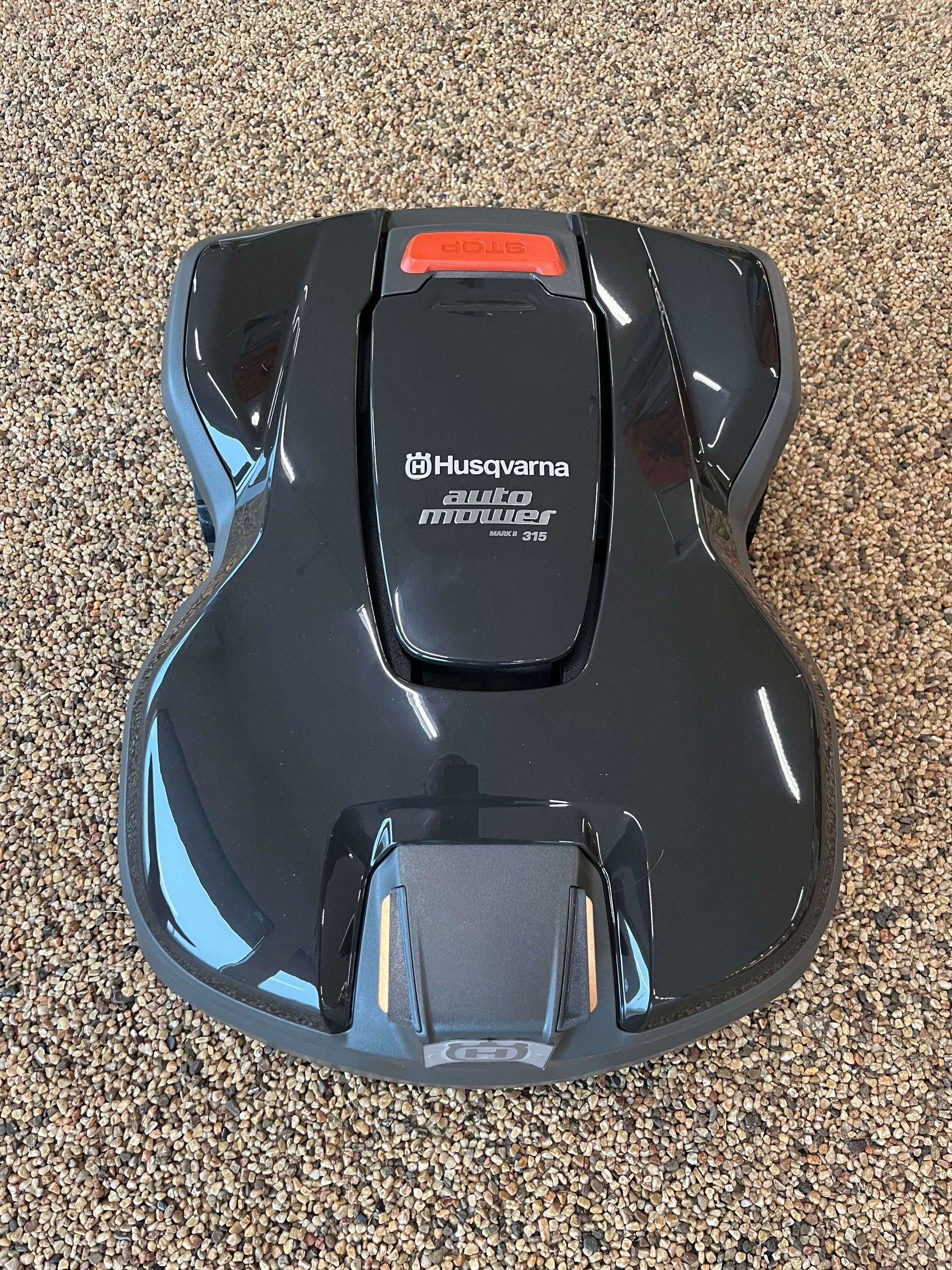 Rød flishugger parkeret på et fortov nær et trådhegn og en tankstation.