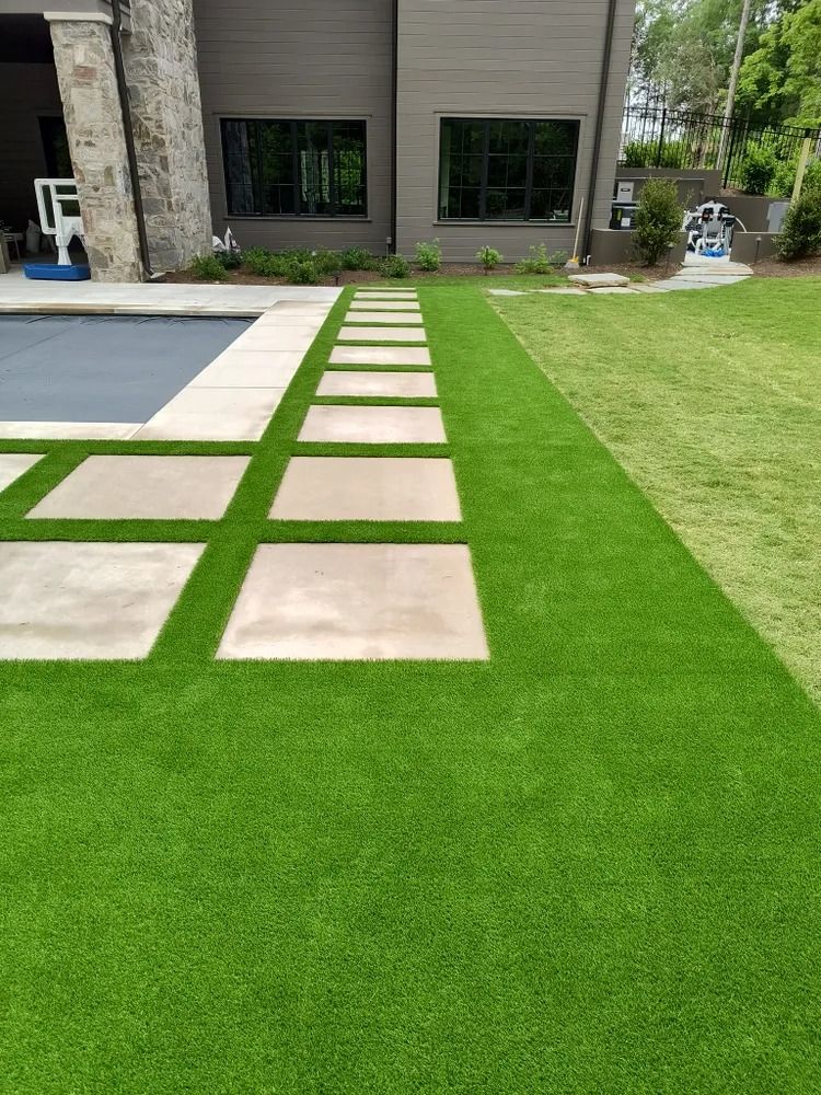 Modern house patio with beige stepping stones set in bright green grass beside a pool