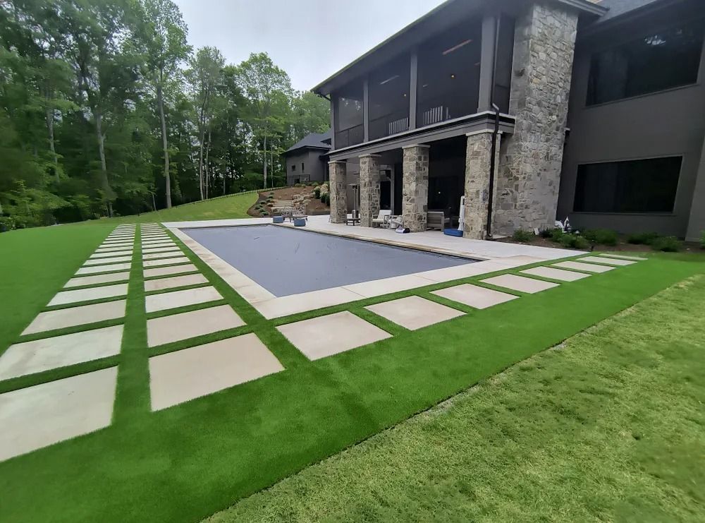 Modern house with stone facade, pool, and geometric stepping-stone patio in a landscaped yard