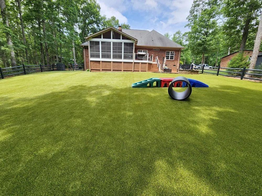 Backyard with a brick house, screened porch, and agility tunnel and ring on a grassy lawn