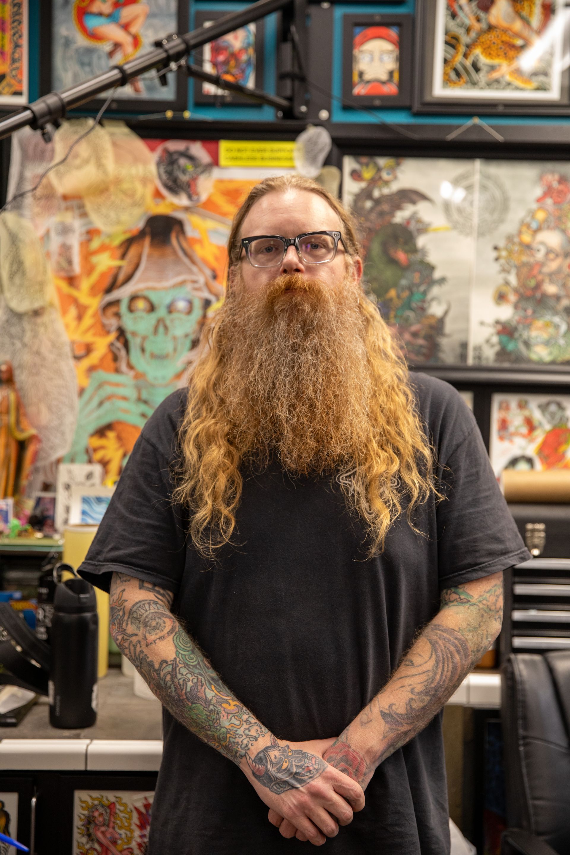 Tattooed man with a long beard standing in a colorful art and tattoo studio