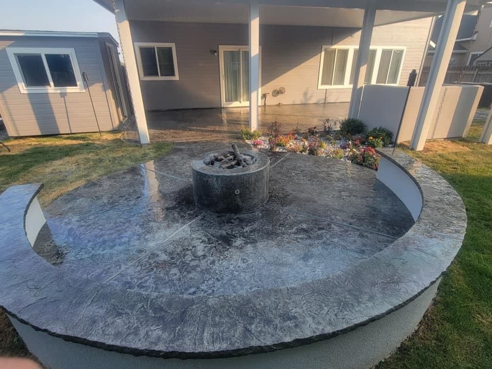 A fire pit is sitting in the middle of a concrete patio in front of a house.