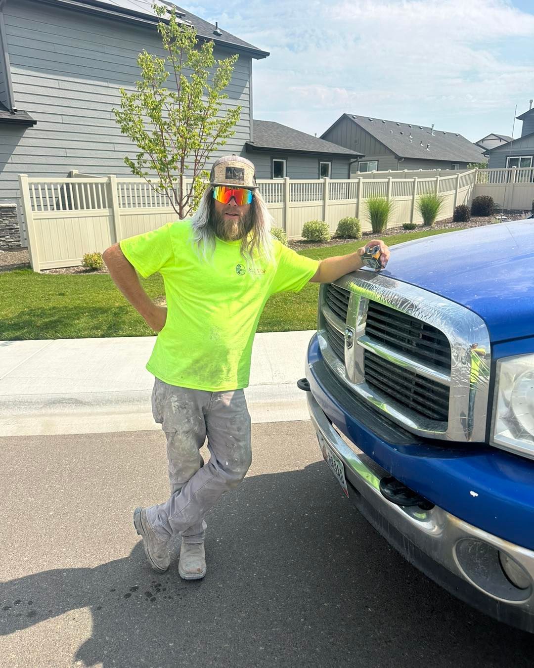 A man in a neon yellow shirt is standing next to a blue truck.